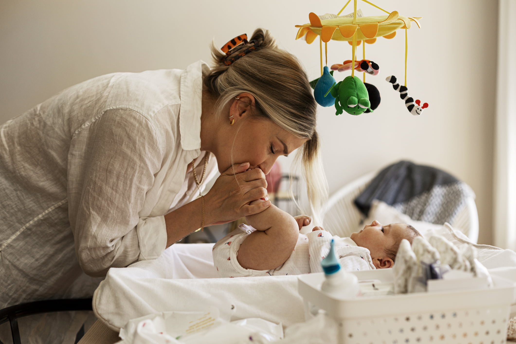 Mor som leikar med baby på stellebord.