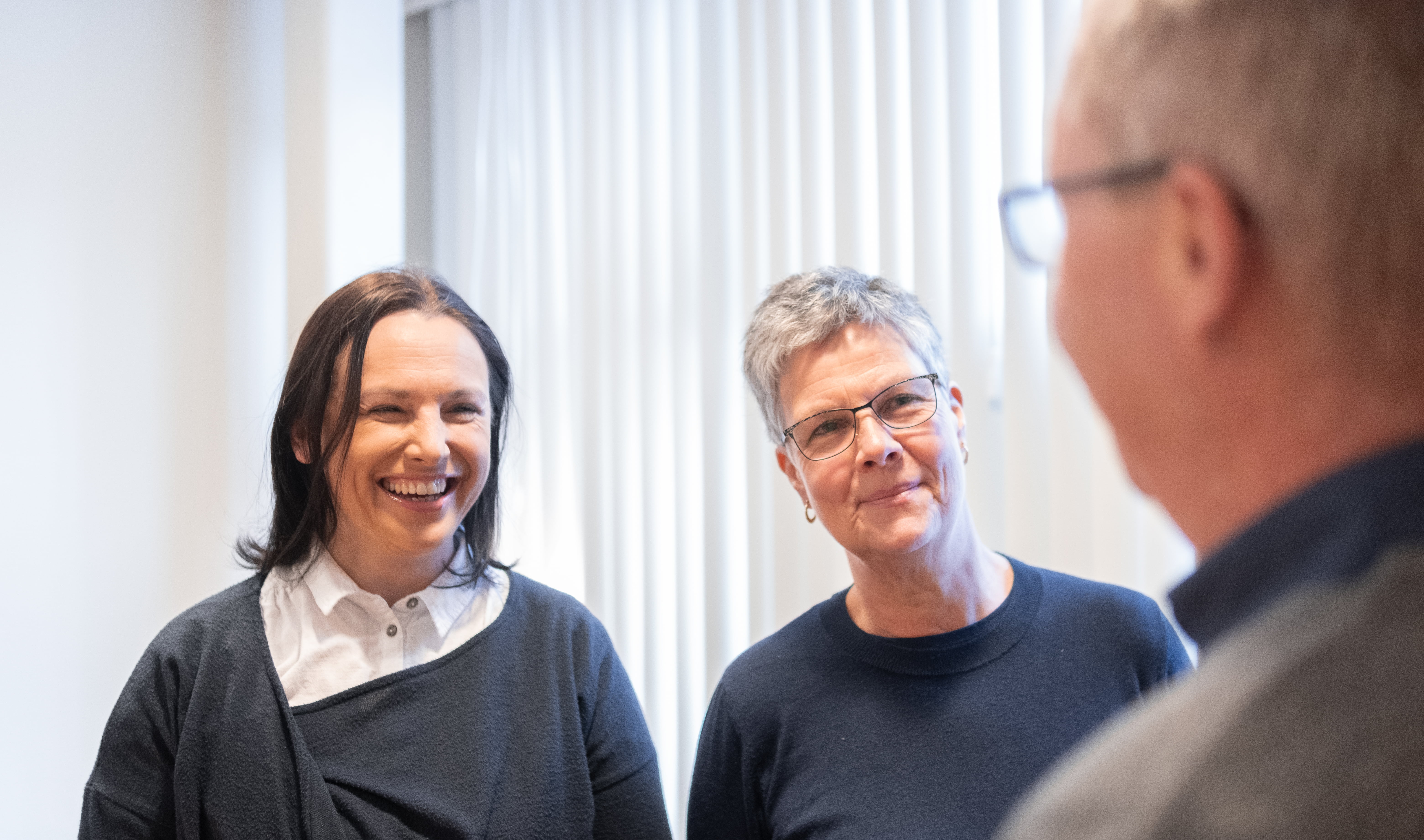 Bilete av to smilende kvinner som ser på en mann