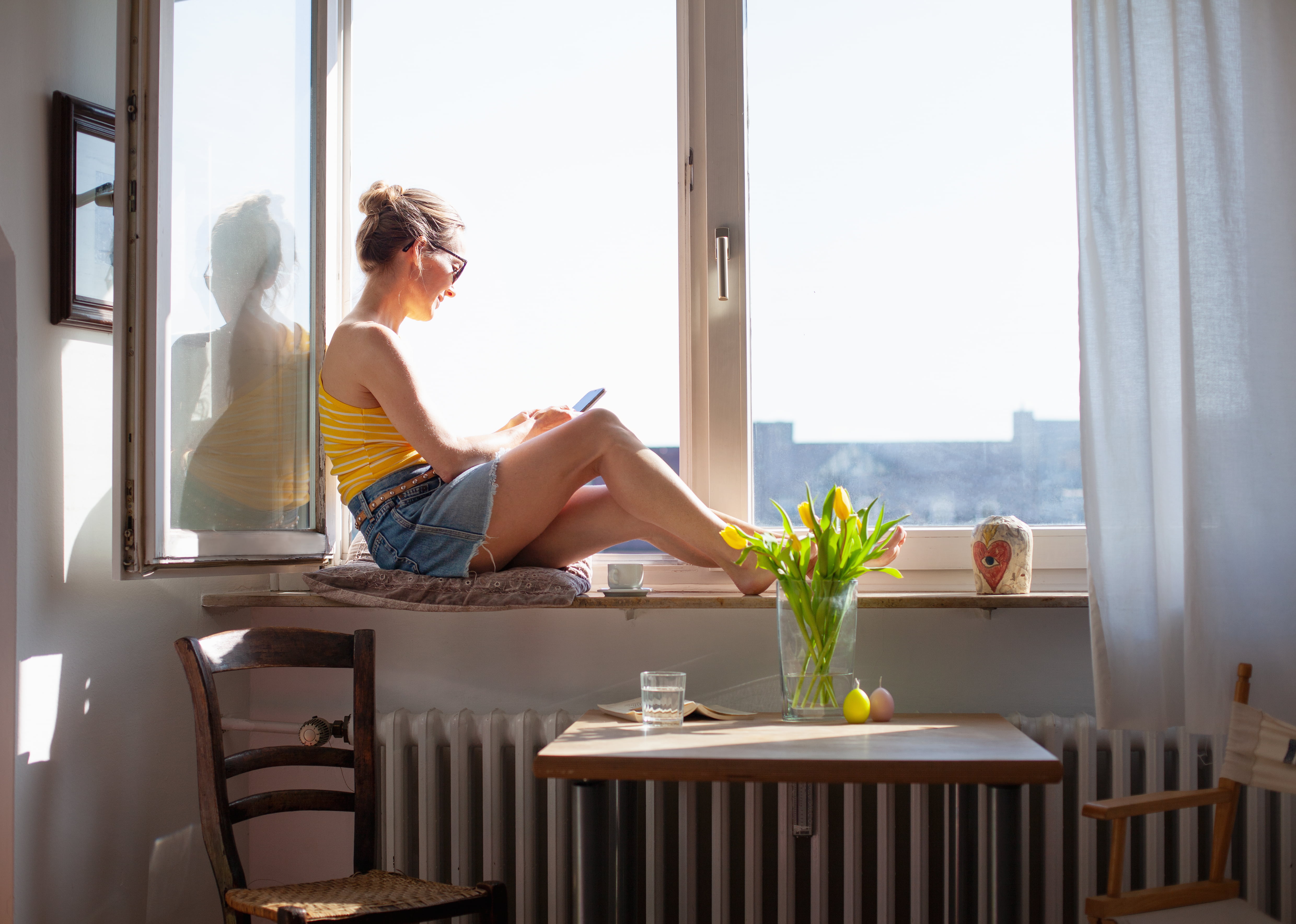 jente i vinduskarmen med telefon i hånden