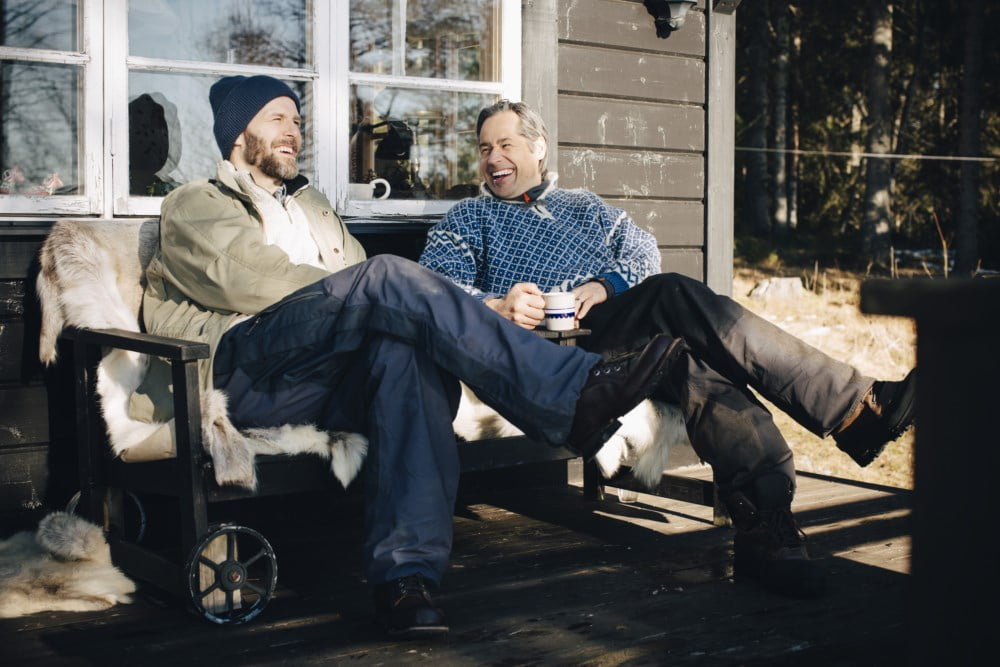 To blide menn som sit på verandaen og drikk kaffi.